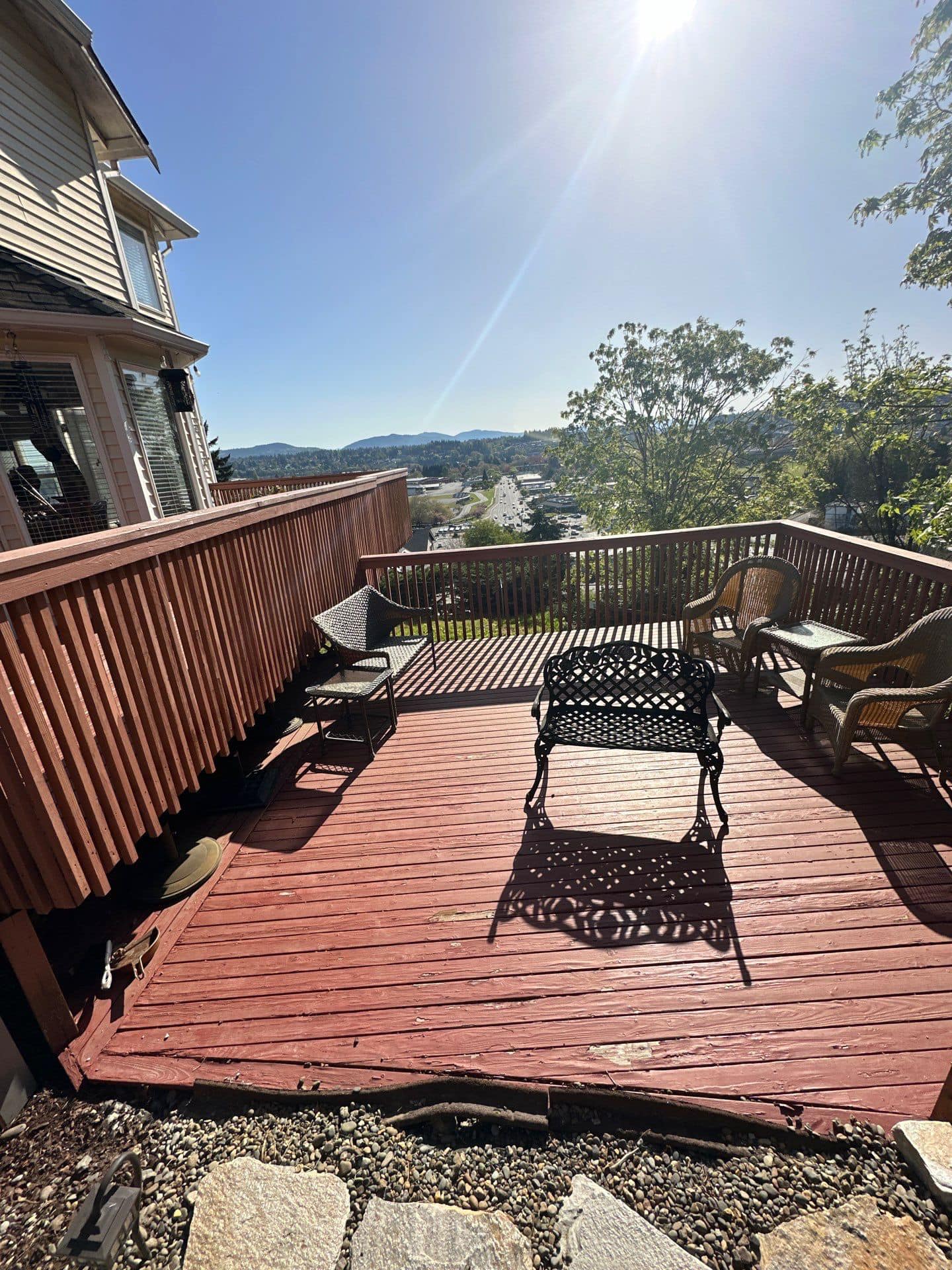 Cedar deck with cast-iron bench overlooking distant mountains on a sunny PNW day